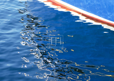 Painted boat lines reflected in blue lake water as abstract art