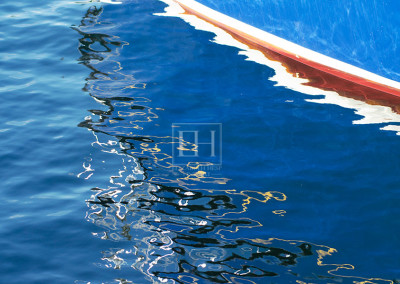 Painted Boat Lines reflected on blue lake water as abstract photographic image