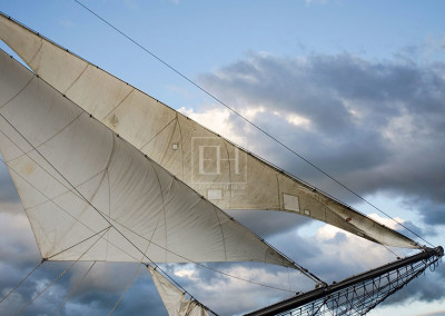 Silver Sails of a tall ship photographed by Elizabeth Hesp against a blue grey sky