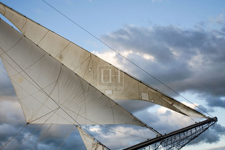 Silver Sails of a tall ship photographed by Elizabeth Hesp against a blue grey sky